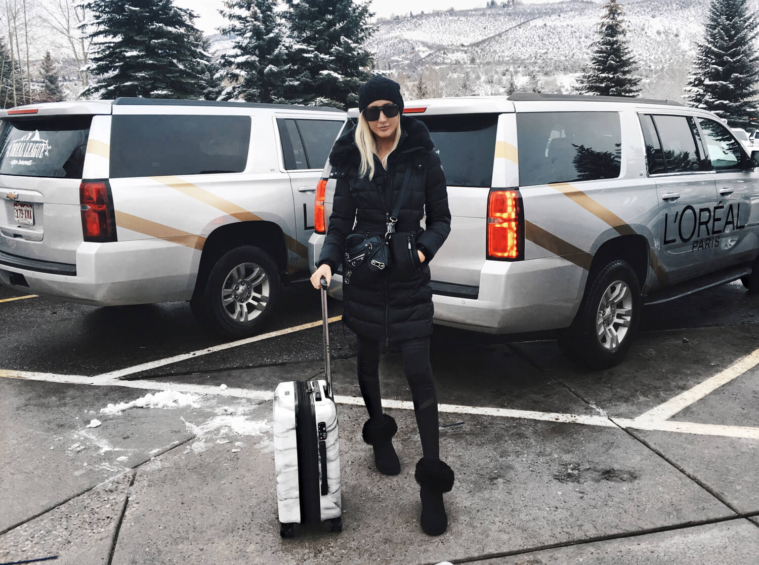Airport Outfits, Cute Airport Outfits for Winter, Carly Cristman wearing Vince Camuto puffy jacket, Alo Moto Leggings, UGG boots, CalPak White Marble Suitcase