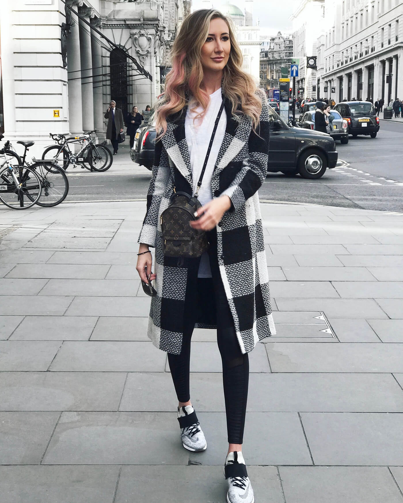 Carly Cristman in London wearing a plaid coat with nike air zoom sneakers and moto leggings