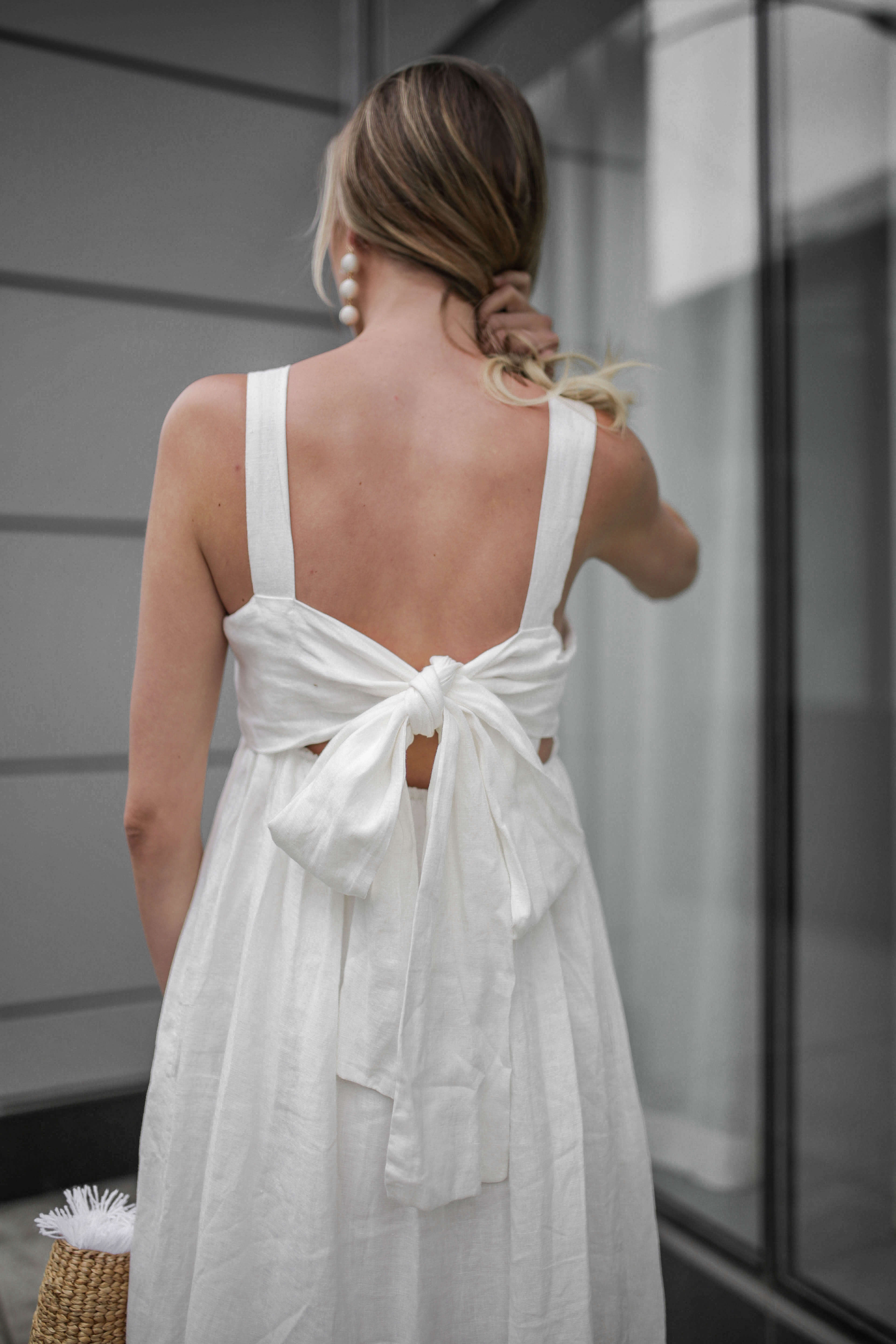 Carly Cristman wearing a summer white linen dress with bow back, Summer Trends 2018, CAARA Forget Me Not Linen Midi Dress, basket bag