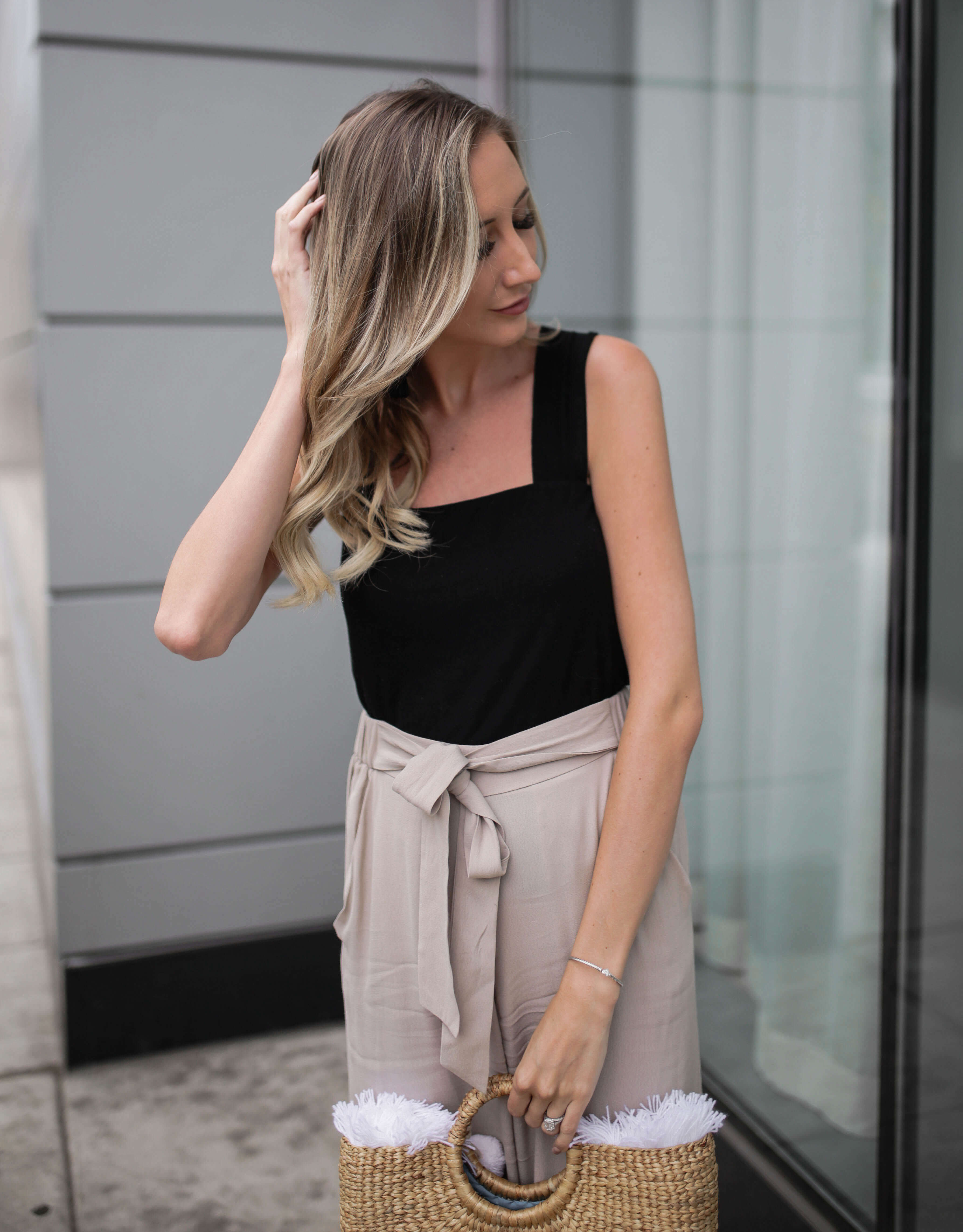 Carly Cristman wearing black tank top with taupe beige flowy cropped pants culottes. Summer outfit inspiration, basket bag, straw bags, easy summer outfits, neutral summer outfit, summer work attire